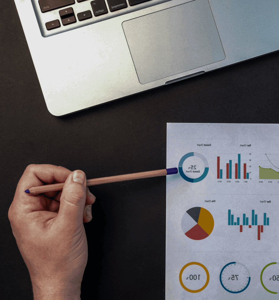Osoba wskazująca ołówkiem na wykresy i statystyki, analizując trendy rynkowe i efektywność strategii sprzedażowej.
